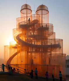 people are standing outside in front of a large structure that looks like a spiral staircase