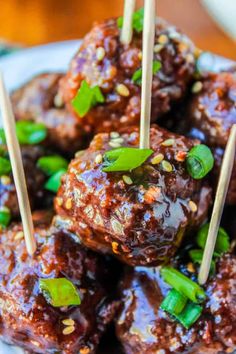 meatballs with green onions and sesame seeds on skewered sticks in a white bowl