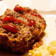 a piece of meatloaf with ketchup and mustard on a white plate