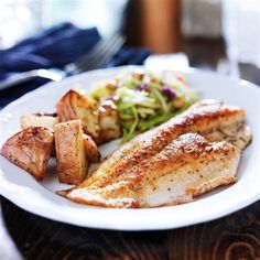 a white plate topped with fish and potatoes