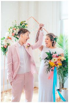 a newly married couple holding hands and standing in front of confetti streamers