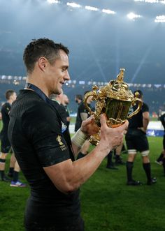 a rugby player holding up a trophy on the field