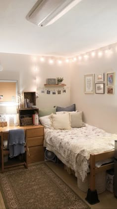 a small bedroom with a bed, desk and lights on the wall above it's headboard