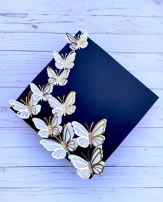 several white and gold butterflies on a black card