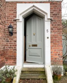 a grey door is open in front of a brick building