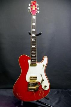 a red and white guitar sitting on top of a stand