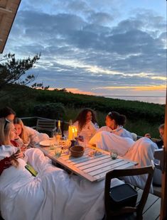 a group of people sitting around a table with food and drinks on top of it