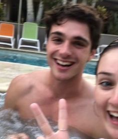 a man and woman in a hot tub making the peace sign