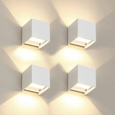 four square lights are mounted on the wall in three different positions, one is white