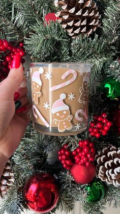 someone is holding a candle in front of a christmas wreath and pineconi cones