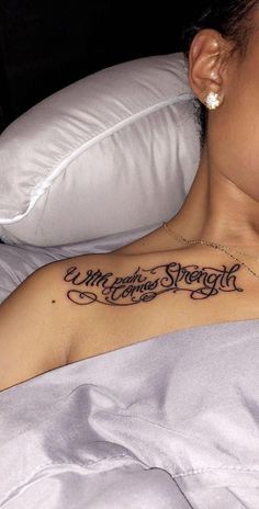 a woman laying in bed with a tattoo on her chest that says merry christmas strength