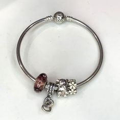 Authentic Pandora sterling bangle bracelet measuring 8".  Has 4 charms.  Has a screw on safety chain 1.  White floral charm 2.  elephant charm 3.  Hanging charm with interlocking hearts 4.  Purple glass bead with crytals Weight 22 gms Excellent condition   Before you buy, please reviews all photos because they are part of our description. All of the items are sold as, so naturally expect some minor imperfections. While preparing items for sale we carefully inspect each piece to make sure that yo Pandora Bracelet Bangle, Pandora Chain Bracelet, Silver Pandora Bracelet, Pandora Bangle Bracelet, Pandora Bangle, Pandora Bracelet Silver, Pandora Armband, The Bangles, Charms Pandora