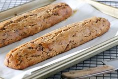 two loaves of bread sitting on top of a baking sheet next to a spatula