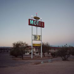 the motel sign is lit up in the evening sun, with no one around it