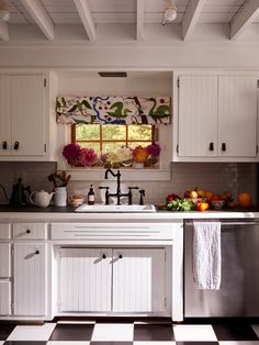 a kitchen with white cabinets and black and white checkered flooring on the floor