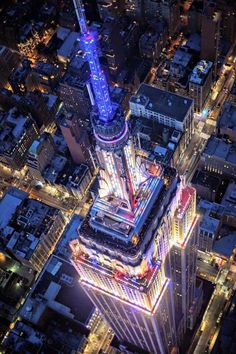 an aerial view of the top of a tall building at night with lights on it