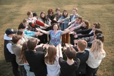 a group of people standing around each other with their arms in the air and one woman holding out her hand