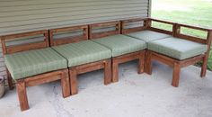 a wooden bench sitting on top of a cement floor next to a wall and grass