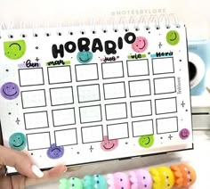 someone is holding up a calendar with smiley faces on it and the word horaq written in cursive writing