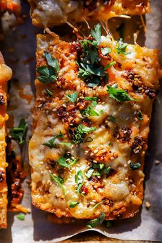 an overhead view of pizza with cheese and herbs on it, cut into squares to be eaten