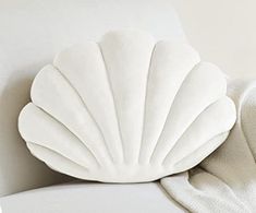 a white shell shaped pillow sitting on top of a couch