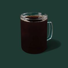 a glass mug filled with liquid on top of a green surface