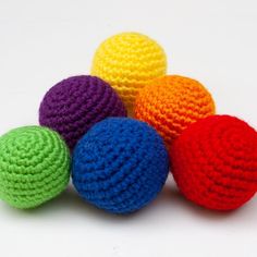 four crocheted balls sitting on top of each other in the middle of a white surface