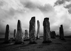 several large rocks sitting on top of a grass covered field under a cloudy sky with dark clouds