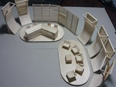 a wooden model of an office cubicle with chairs and desks on it's sides