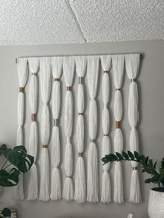 a white wall hanging with tassels and gold accents in a living room area