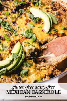 mexican casserole with avocado and cheese in a white dish on a wooden spoon