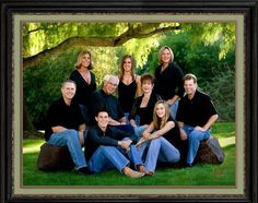 a group of people sitting on top of a lush green field next to a tree