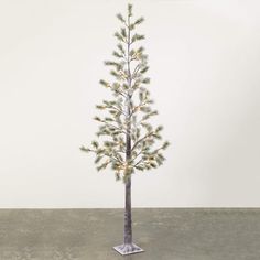 a small christmas tree with white lights in a silver metal stand on concrete flooring