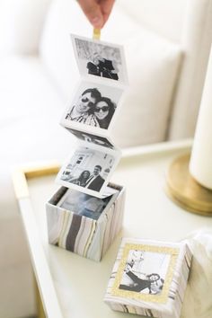 a stack of photos sitting on top of a table next to a candle and pictures