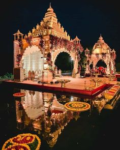 an outdoor wedding setup with lights and flowers on the stage, surrounded by water at night