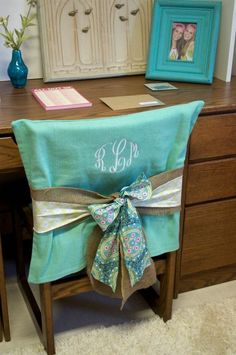 a chair with a bow tied to it sitting in front of a desk and two framed pictures