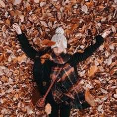 a woman standing in leaves with her arms up