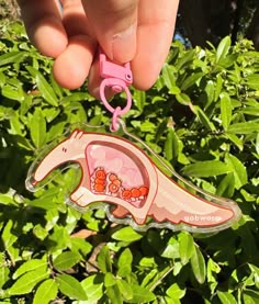 a hand holding a pink keychain with an animal on it