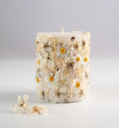 a white candle with yellow and white flowers on it