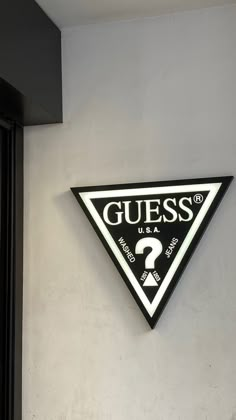 a black and white sign that says guess on the side of a wall next to a door