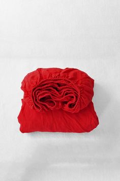 a red blanket folded on top of a white sheet