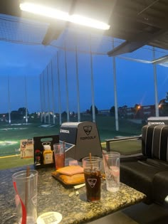 drinks and snacks are sitting on the table in front of an open window at night