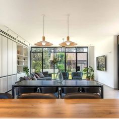 the dining room table is surrounded by black leather chairs and modern lighting fixtures, along with built - in shelving