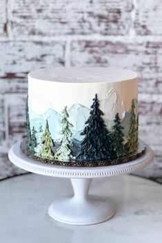 a white cake with trees on it sitting on top of a table