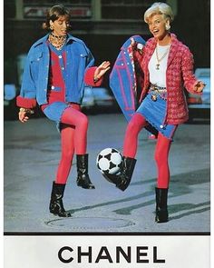 two women in matching outfits are kicking a soccer ball