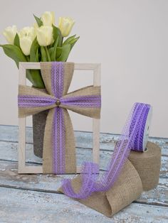 a vase filled with flowers next to a purple ribbon on top of a wooden table