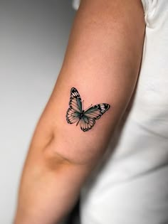 a woman's arm with a butterfly tattoo on the left side of her arm