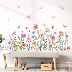 a white bench sitting in front of a wall with flowers and butterflies painted on it