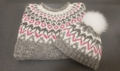 a gray and pink sweater with a white pom - pom