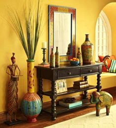 a table with vases, mirror and other decorative items on it in front of a window